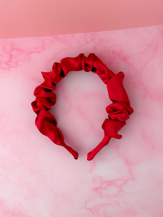 Red satin headband on a pink marble background
