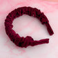 Burgundy velvet headband on a pink and white marble surface