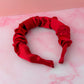 Red satin headband on a pink and white marble surface