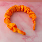 Orange satin headband on a pink marble surface